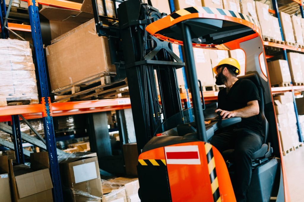 Warehouse worker doing logistics work with forklift loader